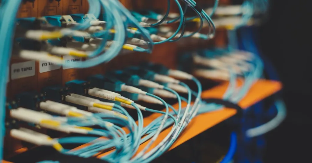 Closeup of many cables with blue wires plugged in modern switch with similar adapters on blurred background in modern studio