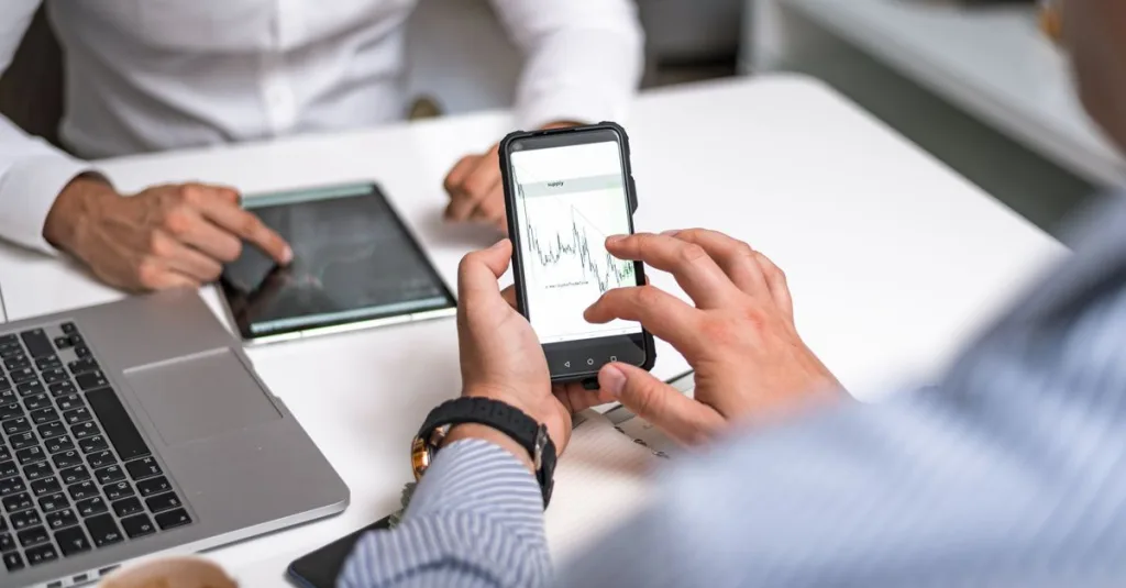 Two business professionals analyzing market trends on digital devices in an office setting.